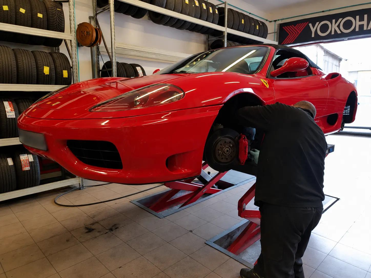 Tecnico al lavoro su una Ferrari rossa in officina